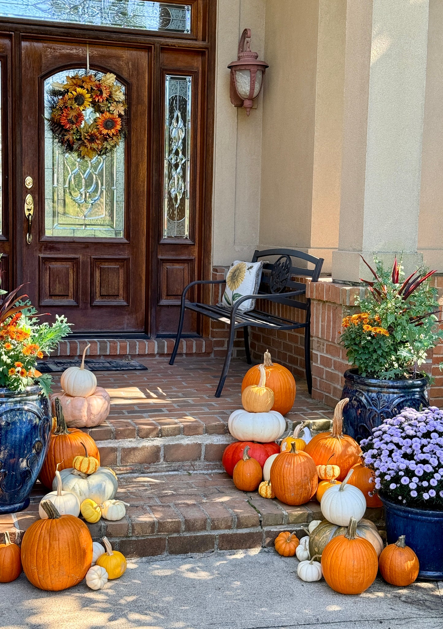 Front porch with pumpkins, flowers, and a decorative wreath on a wooden door. fairy dust and rust 