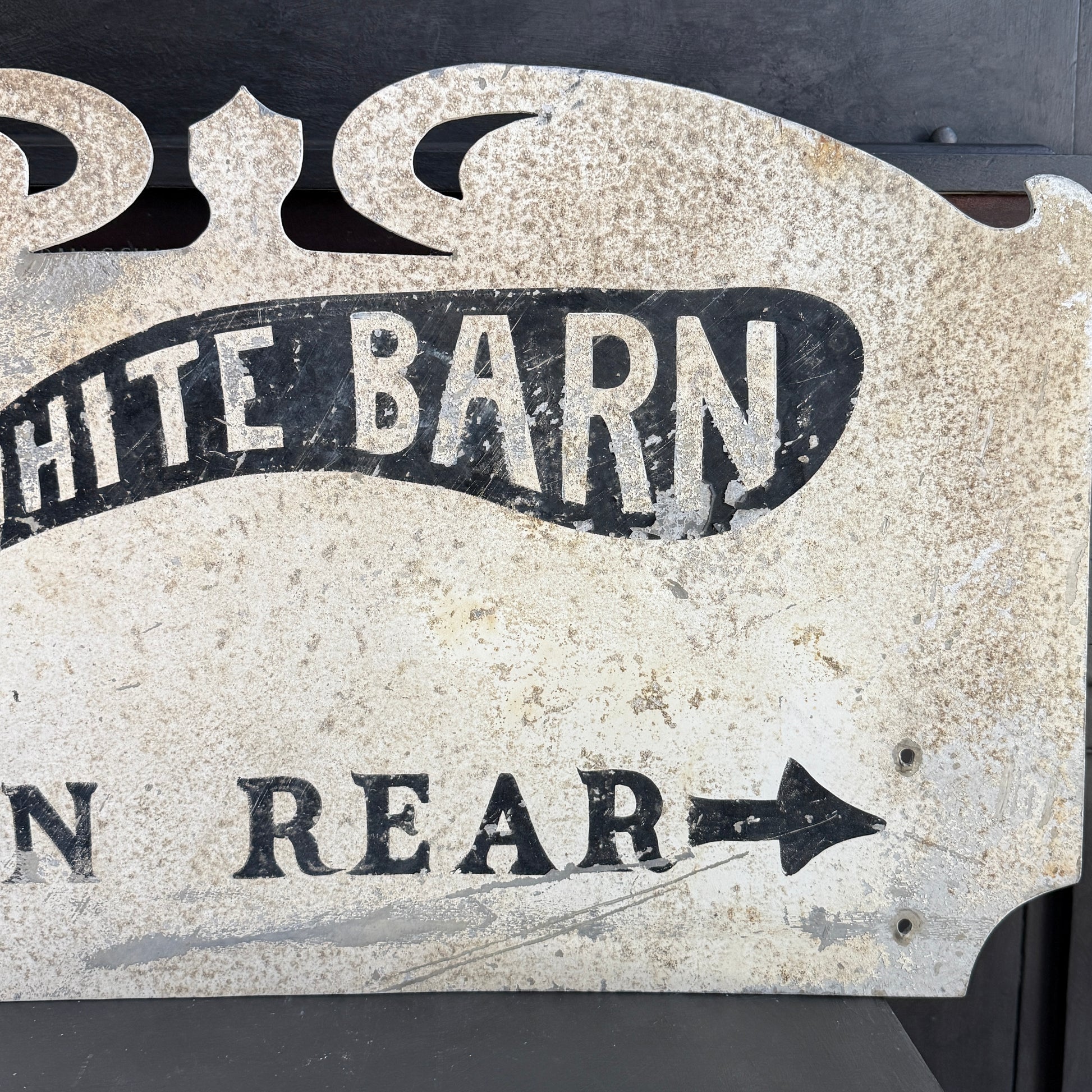 Vintage-style metal sign with 'White Barn' and arrow text on a dark background