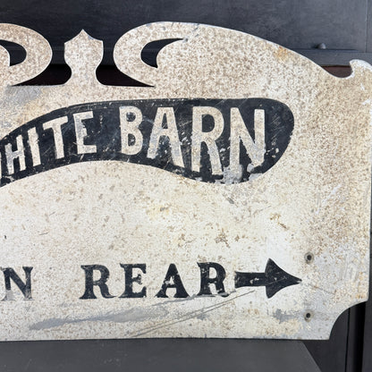 Vintage-style metal sign with 'White Barn' and arrow text on a dark background