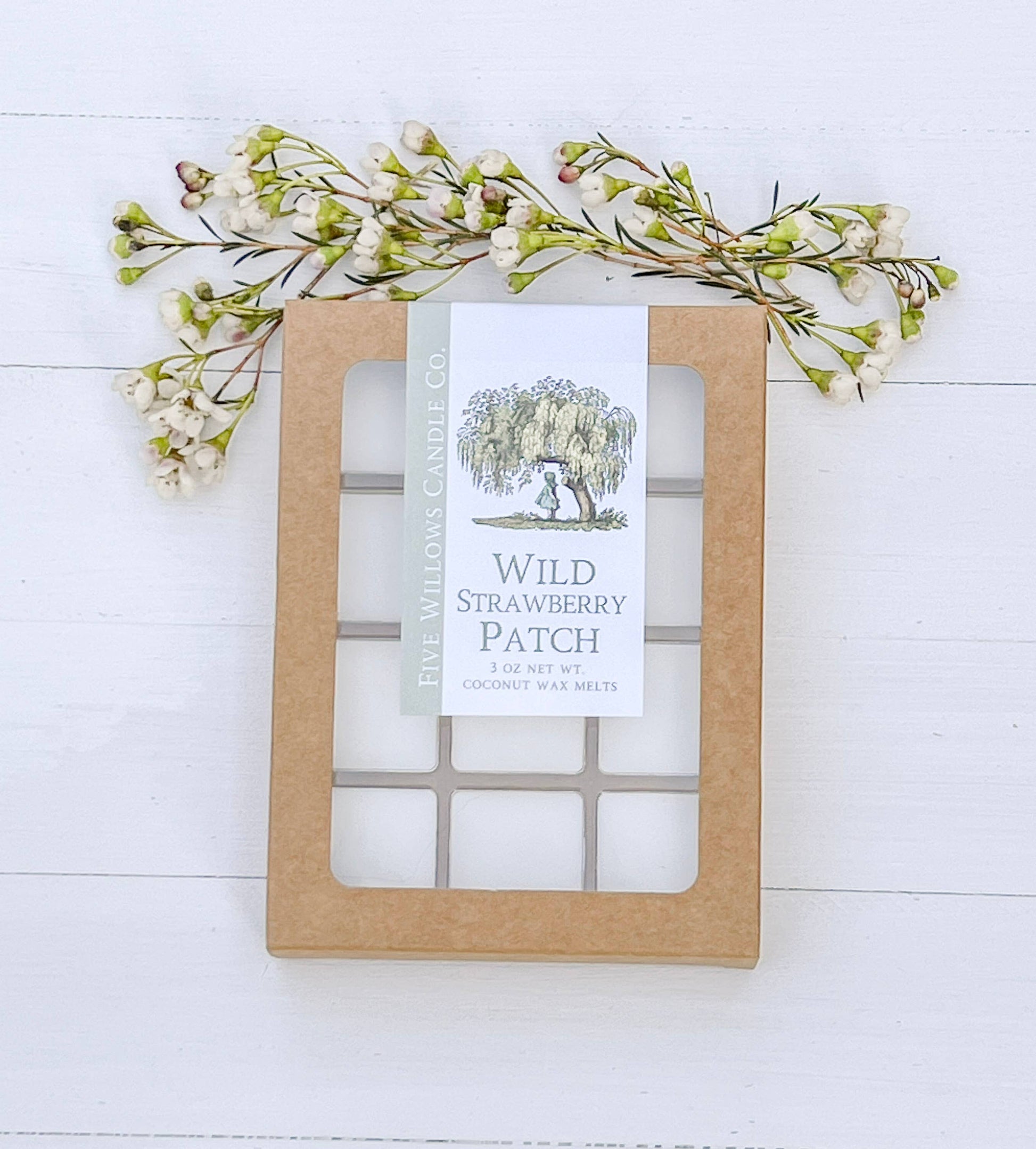 Wax melt packaging labeled 'Wild Strawberry Patch' with decorative floral elements on a white wooden background.