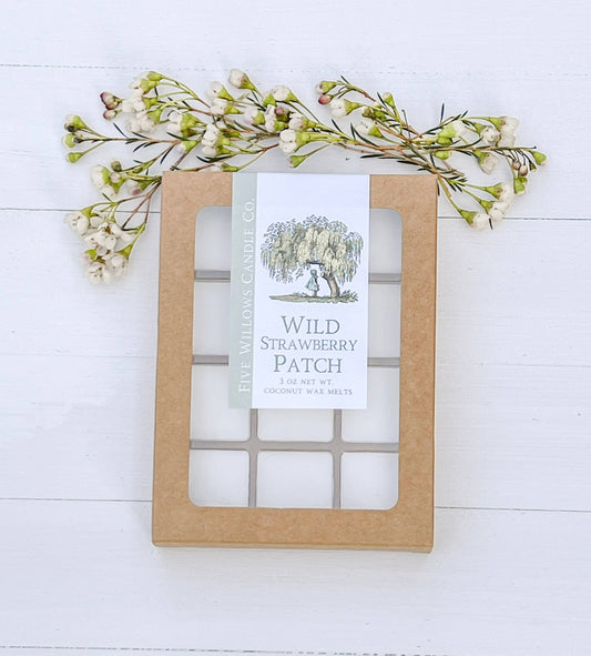 Wax melt packaging labeled 'Wild Strawberry Patch' with decorative floral elements on a white wooden background.